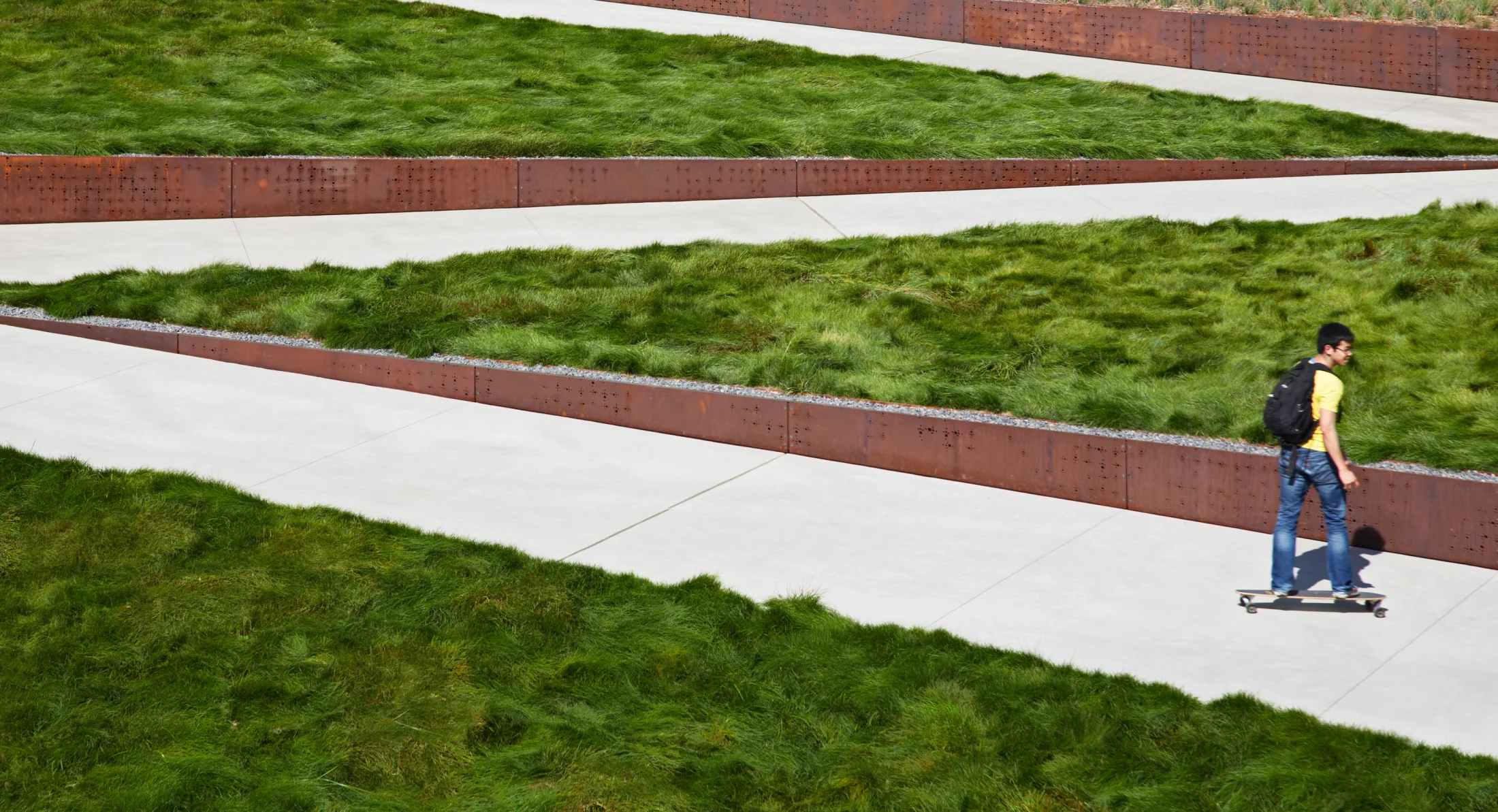 Green meadow planting and angular paths edged in weathered steel beside the IGI building