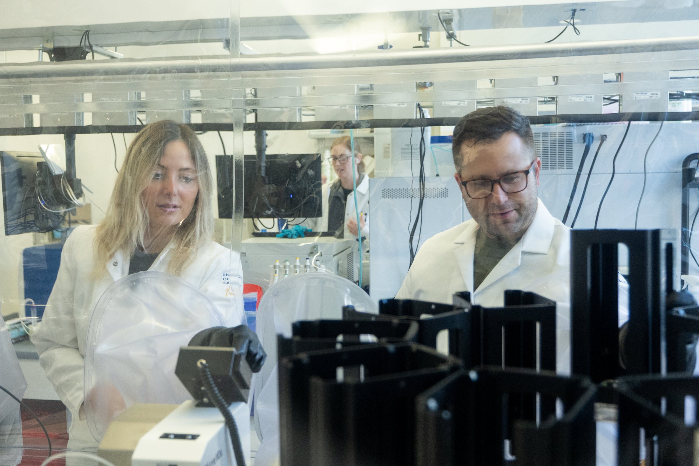 Two lab members at the anaerobic chamber with spectrophotometers